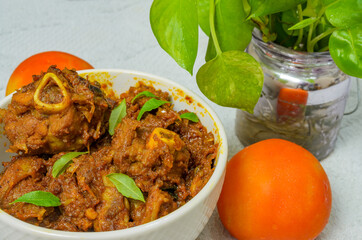 Yummy Mutton Roast in a white bowl along with a tomato.