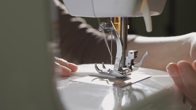 A Female Hand Pushes Material Through A Sewing Machine