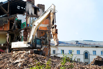 excavator demolishing a brick building. Machinery Demolishing Building