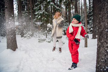 Fototapeta na wymiar Fun family games outdoors on a cool winter morning, mom and son play in the woods.
