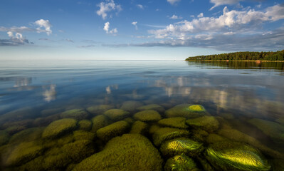 Baltic sea shore in Estonia. Daytime. Rocky sandbank under the clear water of Baltic sea.