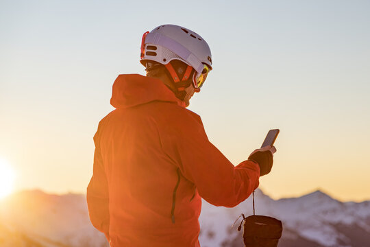 Male skier in the mountains looking at his phone