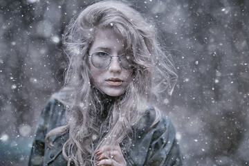 girl romantic portrait first snow autumn, snowflakes blurred background seasonal winter