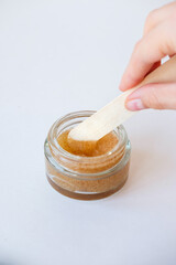 Hand skin care using scrub. Girl with a stick takes scrub from a can