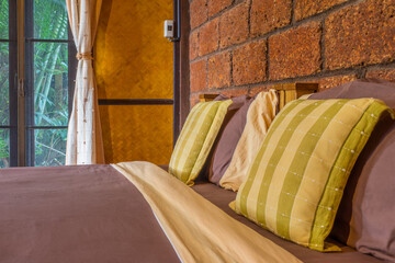 Interior decoration of bedroom with laterite and wicker wall. It consists of double wooden bed,...