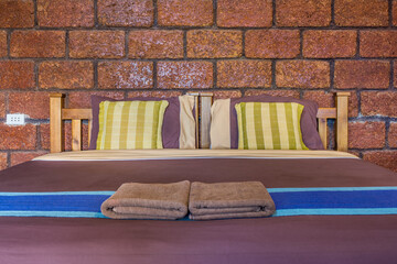 Interior decoration of bedroom with laterite wall. It consists of double wooden bed, pillows,...