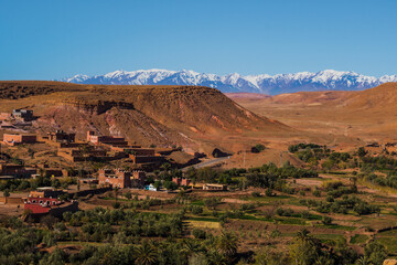 Village Tamedakhte with its oasis, in the background the snow covered summits of mountain Atlas