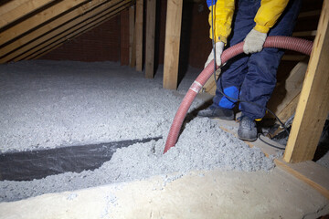 Spraying cellulose insulation in the attic of a house. Insulation of the attic or floor in the house - obrazy, fototapety, plakaty