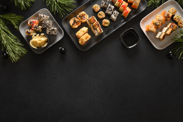 Festive Christmas asian food with sushi set, holiday decoration on black background. View from above. Flat lay style. New Year party.