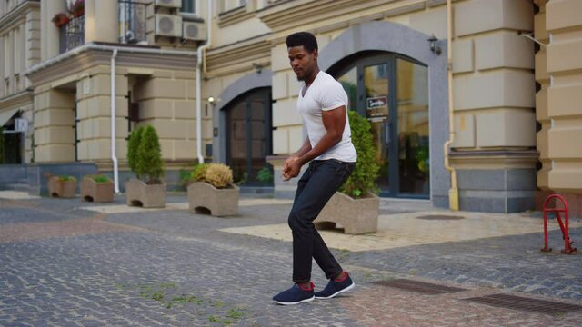 Afro guy dancing latino dance on street. Male dancer making body moves in city
