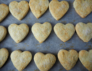 close curd cookies sprinkled with sugar laid out on parchment paper after baking top view . baking at home for Valentine's Day, holidays