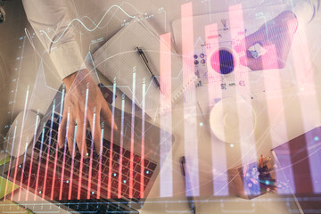 Multi exposure of man's hands typing over computer keyboard and forex graph hologram drawing. Top view. Financial markets concept.