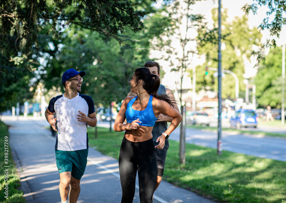 Wall mural Group of young people in sports clothing running in city park.