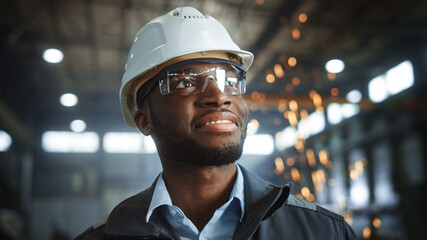 Happy Professional Heavy Industry Engineer/Worker Wearing Uniform, Glasses and Hard Hat in a Steel...