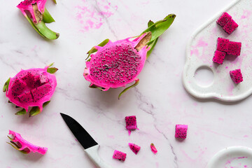 Ugly food. Juicy pink dragon fruit, pitaya, pitahaya sliced on marble table. Trendy top view with...