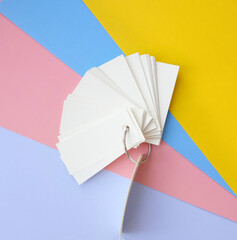 Multicolored background from sheets of paper and stack of blank sheets mockup tied with a metal ring, copy space
