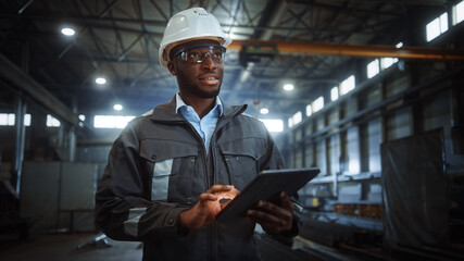 Professional Heavy Industry Engineer/Worker Wearing Safety Uniform and Hard Hat Uses Tablet...