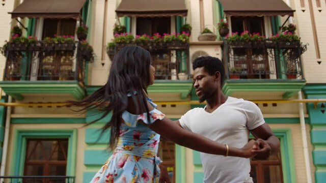 Happy afro dancers curling in latino dance in city. Couple dancing on street