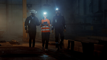 Three Diverse Multicultural Heavy Industry Engineers and Workers Walk in Dark Steel Factory Using...