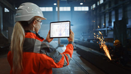 Professional Heavy Industry Engineer Uses Tablet Computer for Checking Metal Gear Blueprints in Interactive CAD Software. Female Industrial Specialist Working in a Metal Manufacture Warehouse.