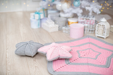 Obraz na płótnie Canvas knitted cotton rug, decorative pillows in shape star lie on near Christmas tree