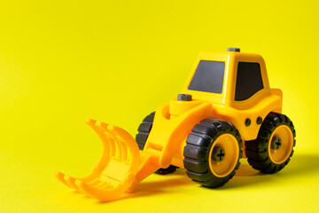 Children's construction machine lumber loader on a yellow background. Tractor for the boy and photo for the toy store with a place for text copy space