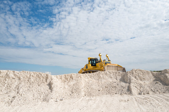 Yellow bulldozer moving limestone in the quarry. Faxe Kalkbrud, Denmark.