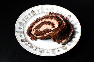 Swiss sponge cake with cream and chocolate on a white plate.