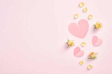 Pink paper hearts and yellow rose buds flowers and petals on pastel pink background. Valentines day flat lay style composition, top view. Love, romance concept.