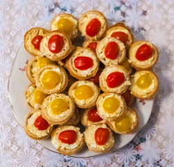 Tartlets with salad and tomatoes on a plate close-up against a white tablecloth