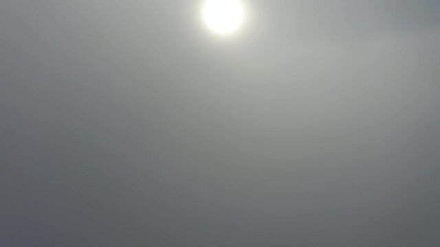 Rising drone shot over thick clouds to blue skies