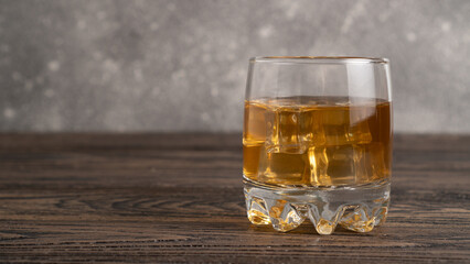 Glass of scotch whiskey and ice on wooden table. A glass of hard liquor. Close up rum in a glass tumbler
