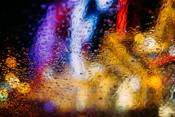 City night lights bokeh background, abstract soft focus concept. Magic background with colorful bokeh. Christmas lights through the wet glass with water droplets 