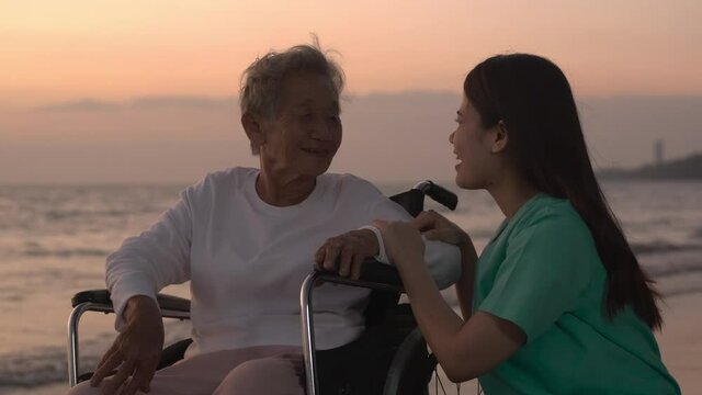 Woman talking with grandmother at the sea. They discussion with funny emotion with sunset background.