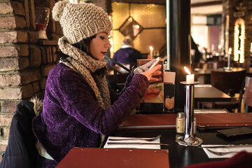 A girl looking at the mobile in a restaurant in Berlin.