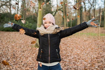 A happy girl throwing leaves in the coming of autumn.