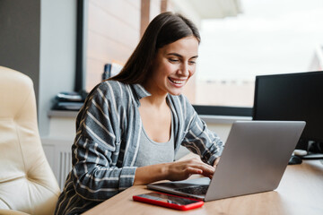 Charming happy woman smiling while working with laptop at home