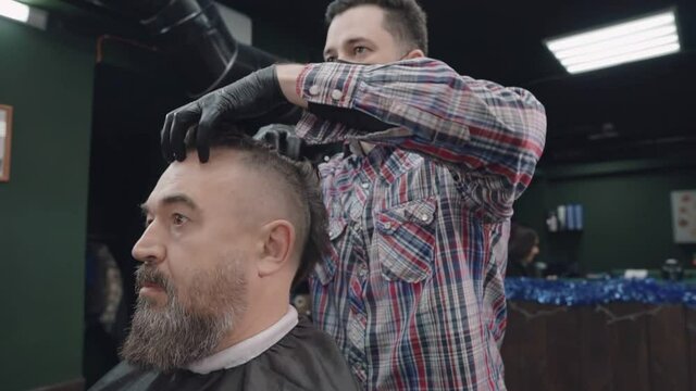 Barber makes a mohawk for a man using hair gel