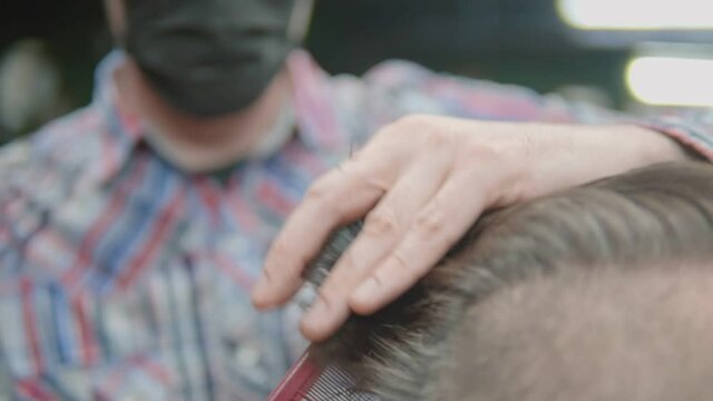 The master cuts his hair with scissors. Close-up.