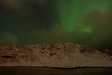 Fototapeta na wymiar Aurora borealis Green northern lights above mountains