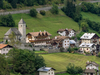 Obraz premium A glimpse of Gomagoi, Stelvio, South Tyrol, Italy, with the parish church and other buildings surrounded by greenery