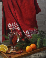 Hot mulled wine with cinnamon sticks, star anise, spruce branches, tangerines, cranberries and a red knitted sweater.