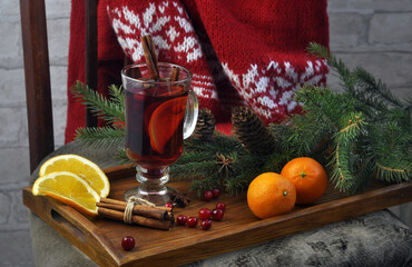 Hot mulled wine with cinnamon sticks, star anise, spruce branches, tangerines, cranberries and a red knitted sweater.