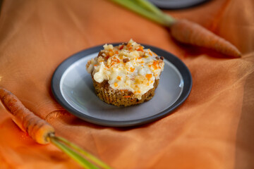 Delicious homemade carrot cupcake or muffin with ingredients on orange organza fabric