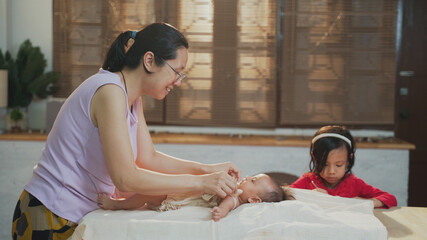 Young Asian mother playing with her infant baby girl while happy and enjoy Christmas holiday at home