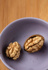 Two walnut in a violet plate on a wooden background on top view Still life photography