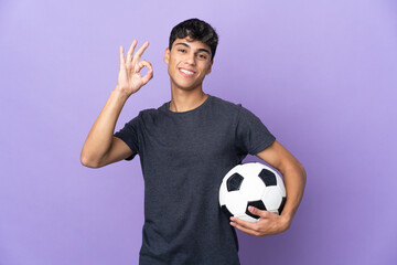 Young football player man over isolated purple background showing ok sign with fingers