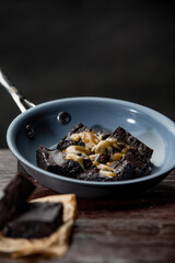 Freshly baked brownies in pan on top of wooden kitchen table over dark background
