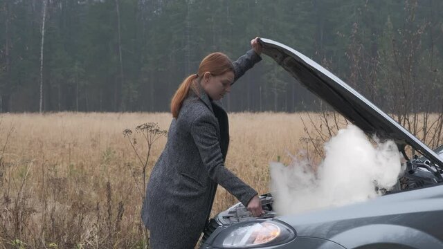 Business woman open the hood and looking at car smoke engine