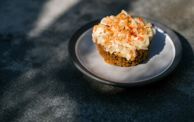 Delicious homemade carrot cupcake or muffin on minimalist stone grey background with shadows